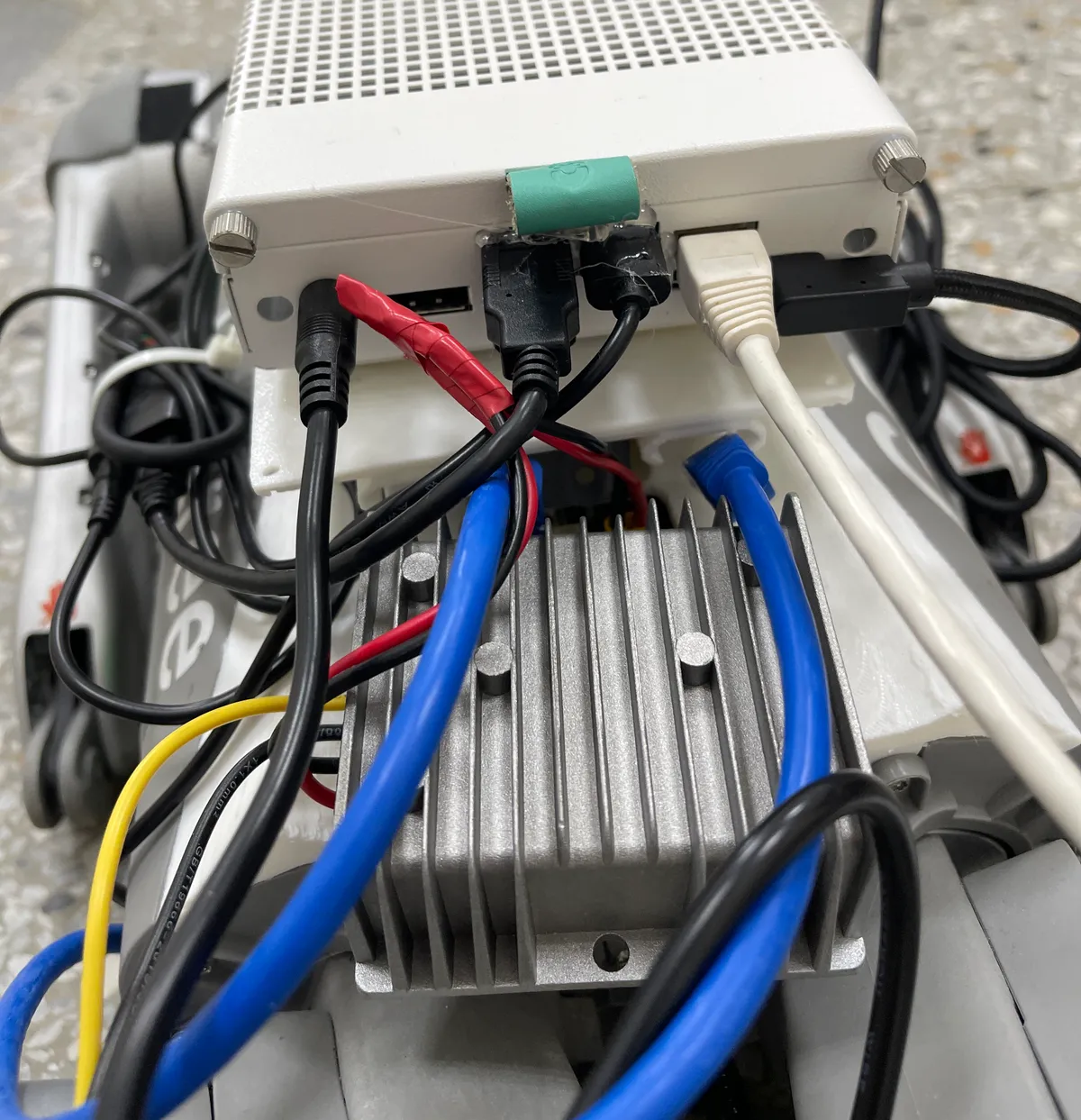Photo: a silver finned aluminum converter mounted on the Go2's back, under the white-and-green Jetson box and cables