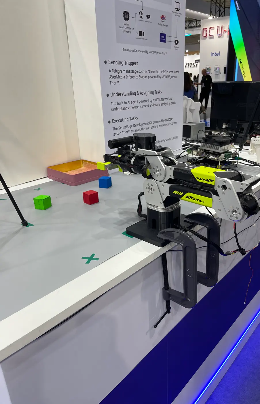 A robot arm with colored cubes on a table, next to a process board