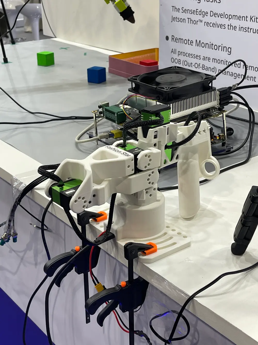 A small white robot arm connected to a Jetson Thor developer kit, with a sign naming the kit