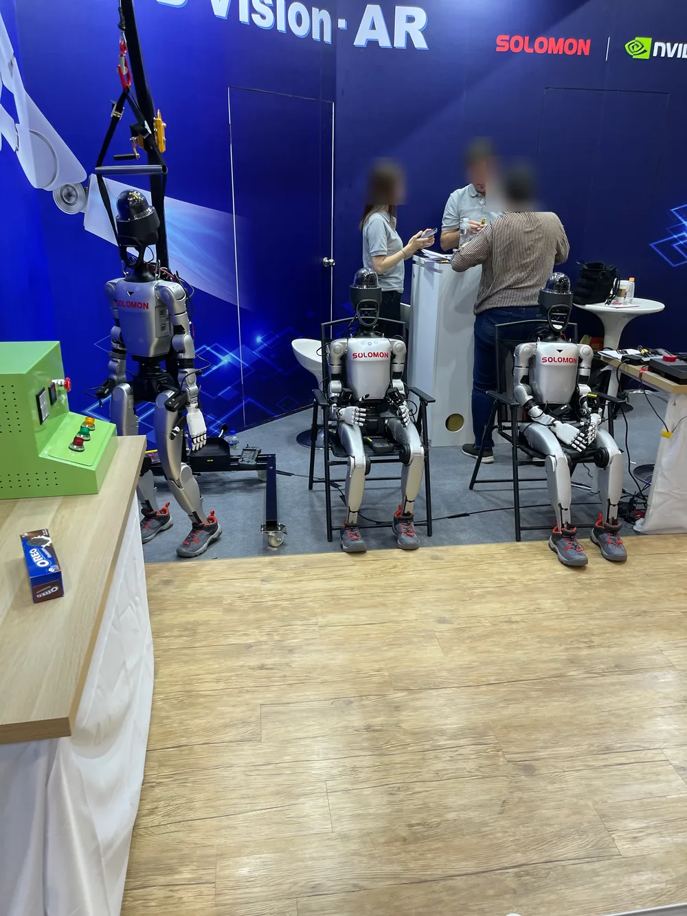 Three humanoid robots displayed side by side at the SOLOMON and NVIDIA booth