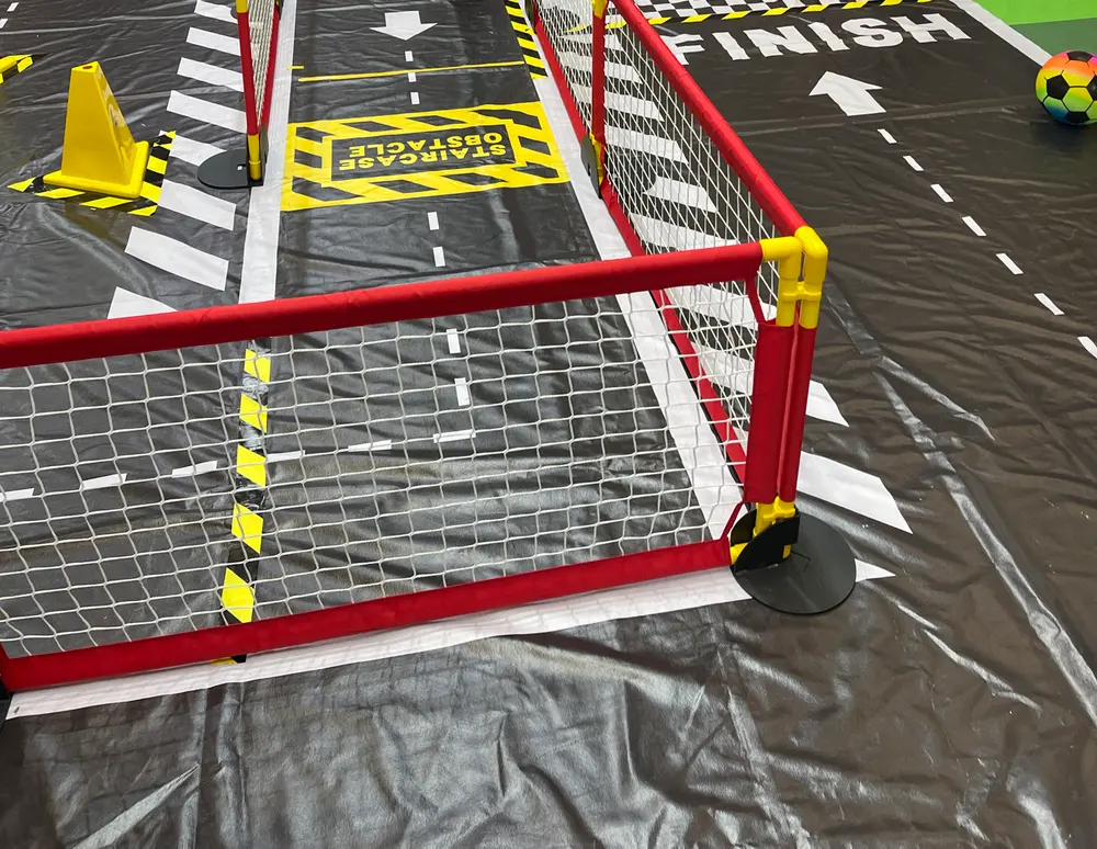 A robot dog test course fenced with red barriers, with obstacles and a finish line on the floor