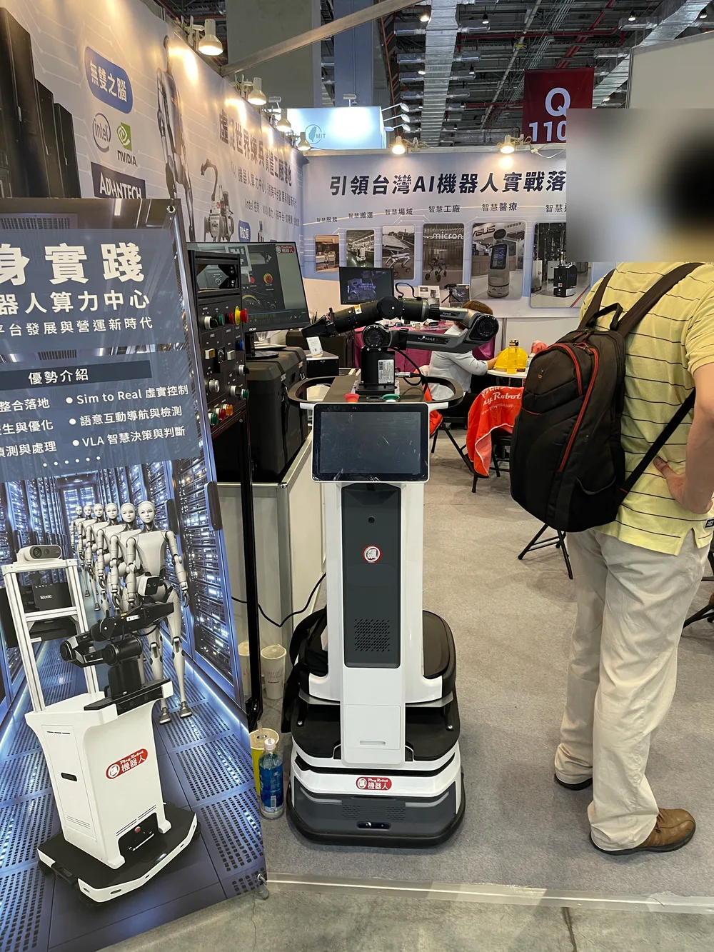 A booth board reading embodied practice and robot compute center, next to a service robot with a screen