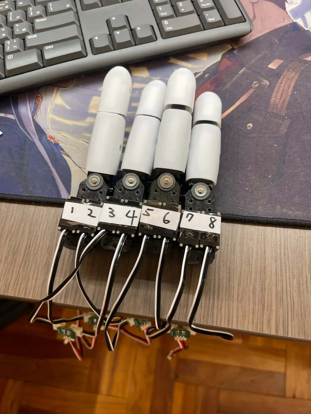 Four assembled fingers lined up, servos labeled 1 to 8
