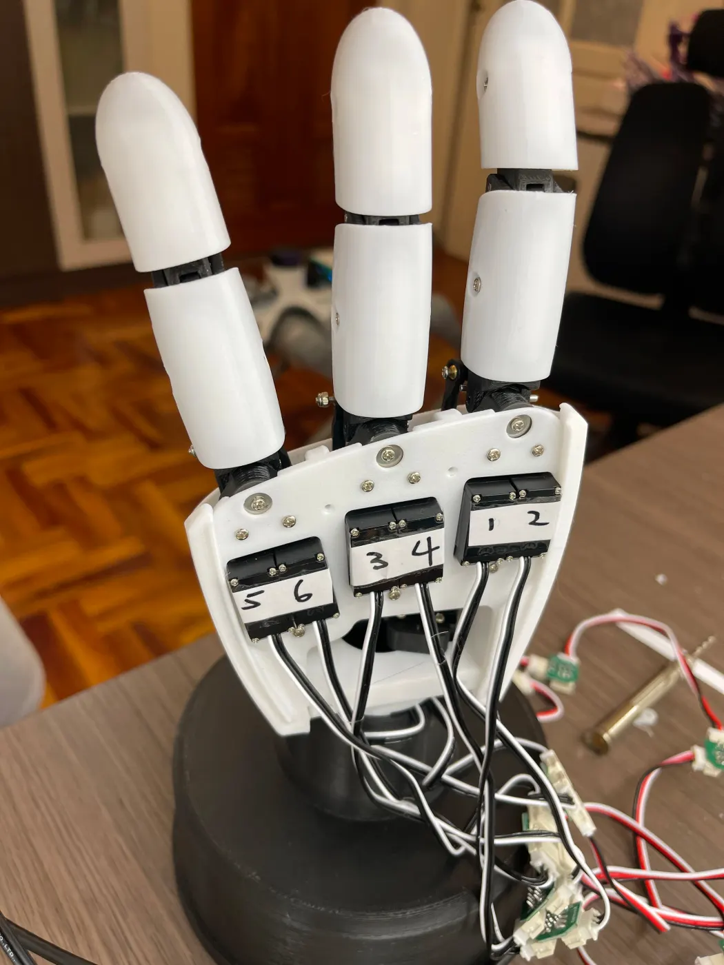 The assembled hand on its black base, servo number labels visible on the palm