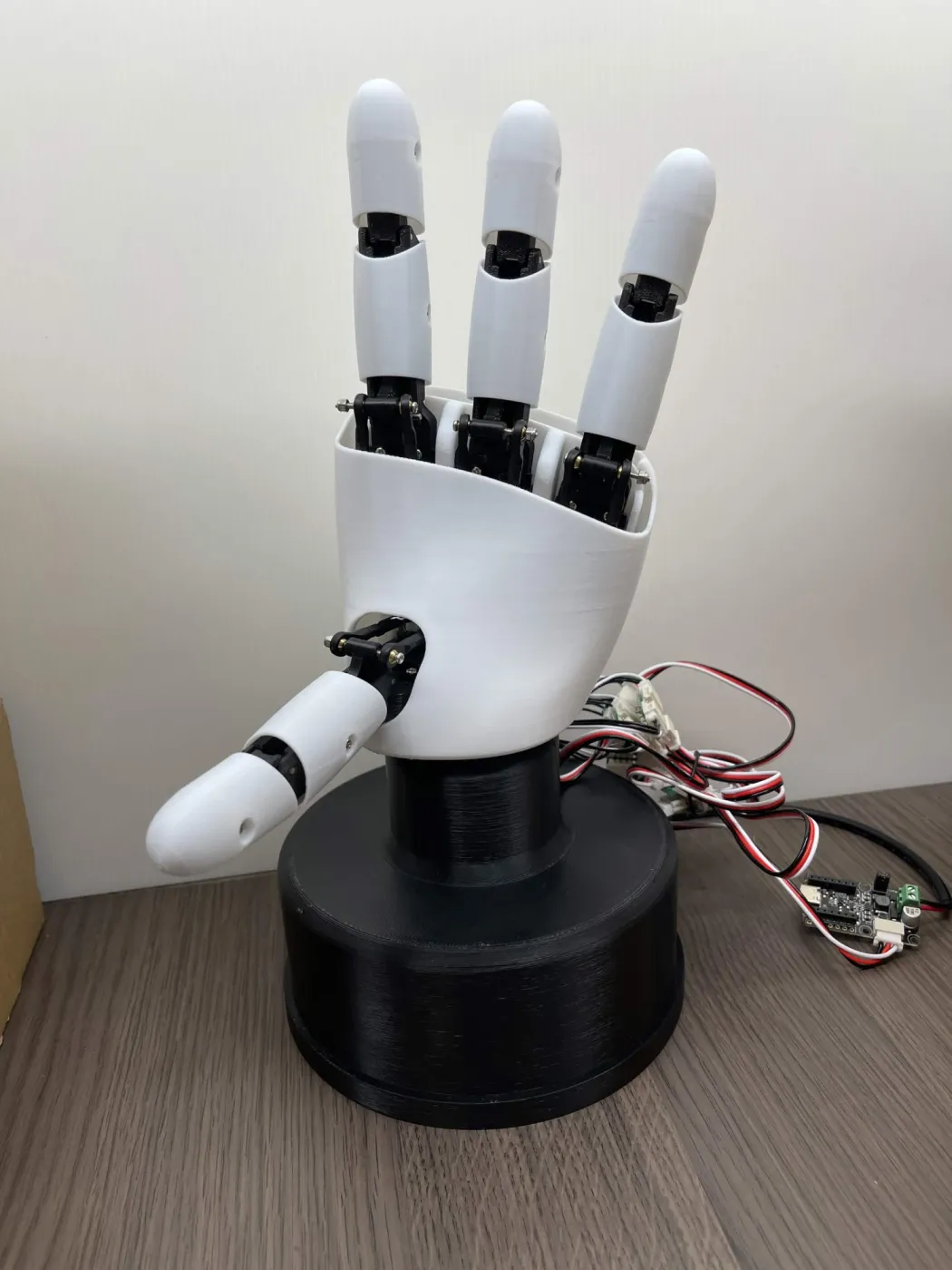 An assembled white AmazingHand on a black base, making a gesture
