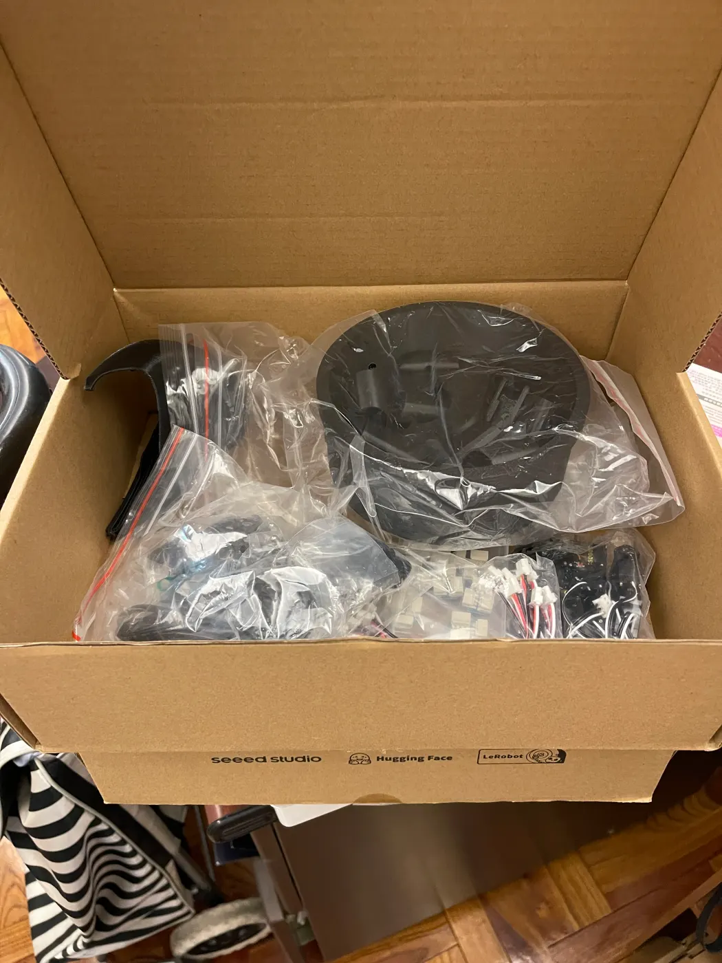 An open kit box full of bags of small parts and a black base