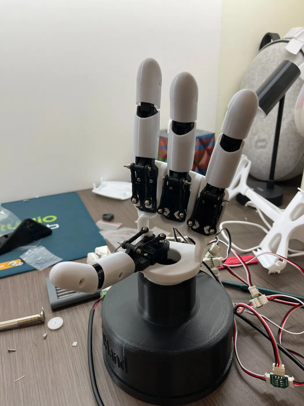 Four fingers mounted on the palm, servos labeled, cables running down to the controller