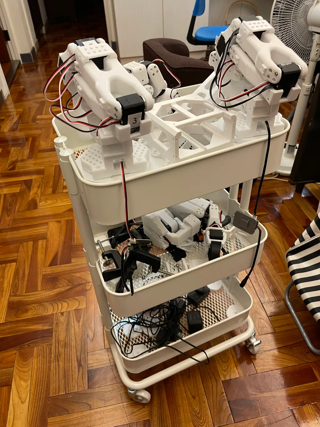 Two arms on the cart's top shelf, cables and power supplies below