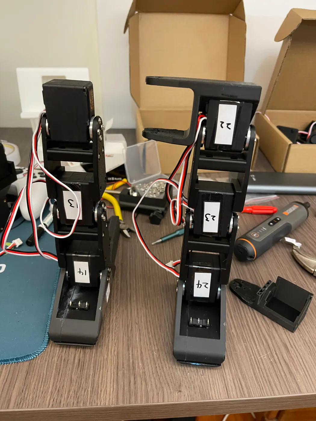 Left and right legs on the desk, each servo with a hand-written number label