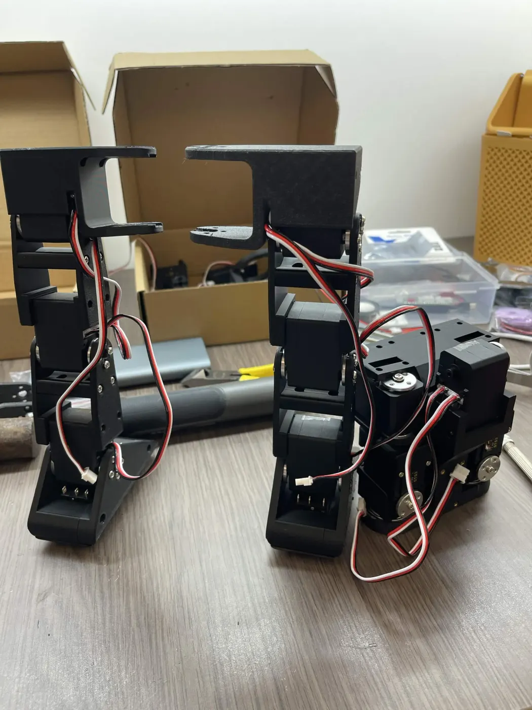 The two legs standing separately on the desk, servo cables hanging loose